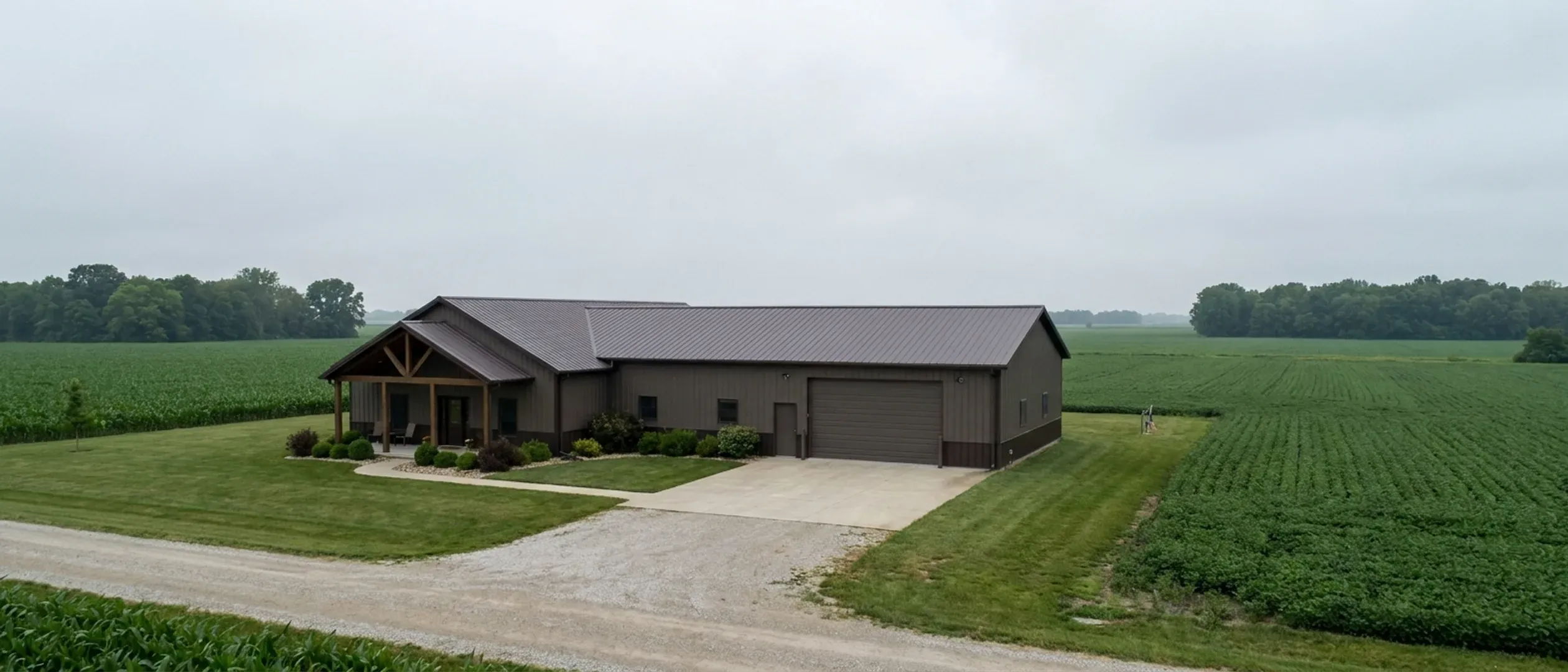 A completed barndominium with a covered entry porch and an attached shop bay, photographed in flat overcast daylight.
