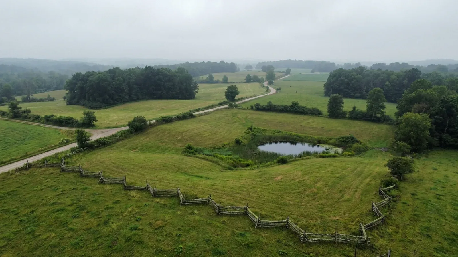 Rolling north-east Ohio country with small hay fields among maple and beech woodlots and a kettle pond in a field hollow.